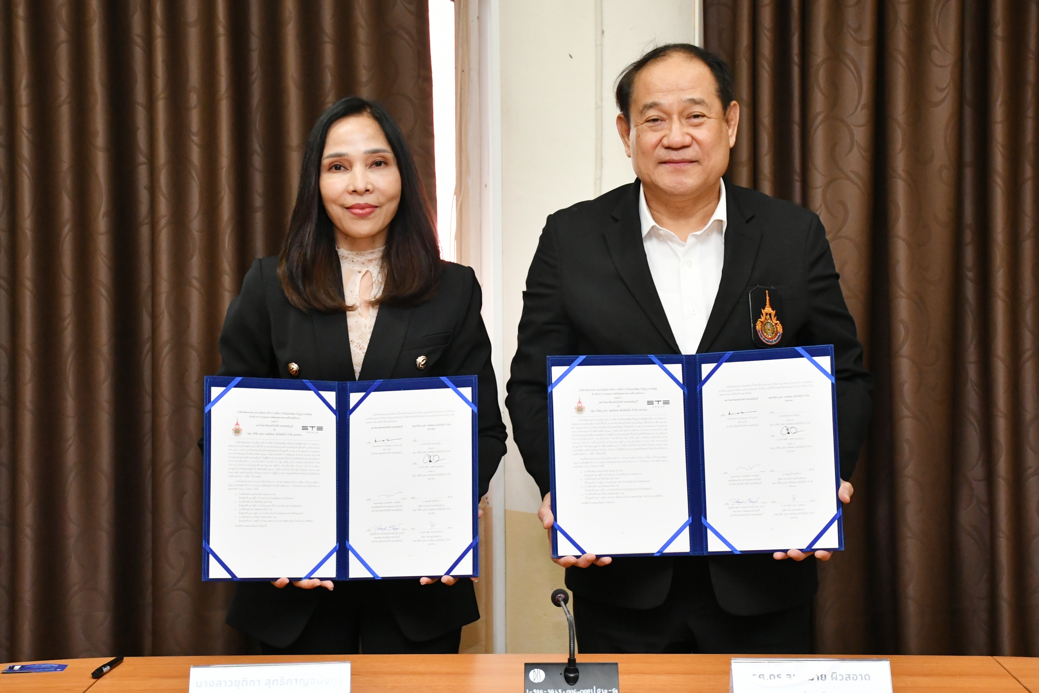 รศ.ดร.สมหมาย ผิวสอาด อธิการบดี RMUTT และ คุณชุติกาญจน์ คงคานนท์ ผู้แทนจาก ETE Group ร่วมถ่ายภาพคู่ขณะถือแฟ้มบันทึกความเข้าใจ (MOU) ที่ลงนามเรียบร้อยแล้ว